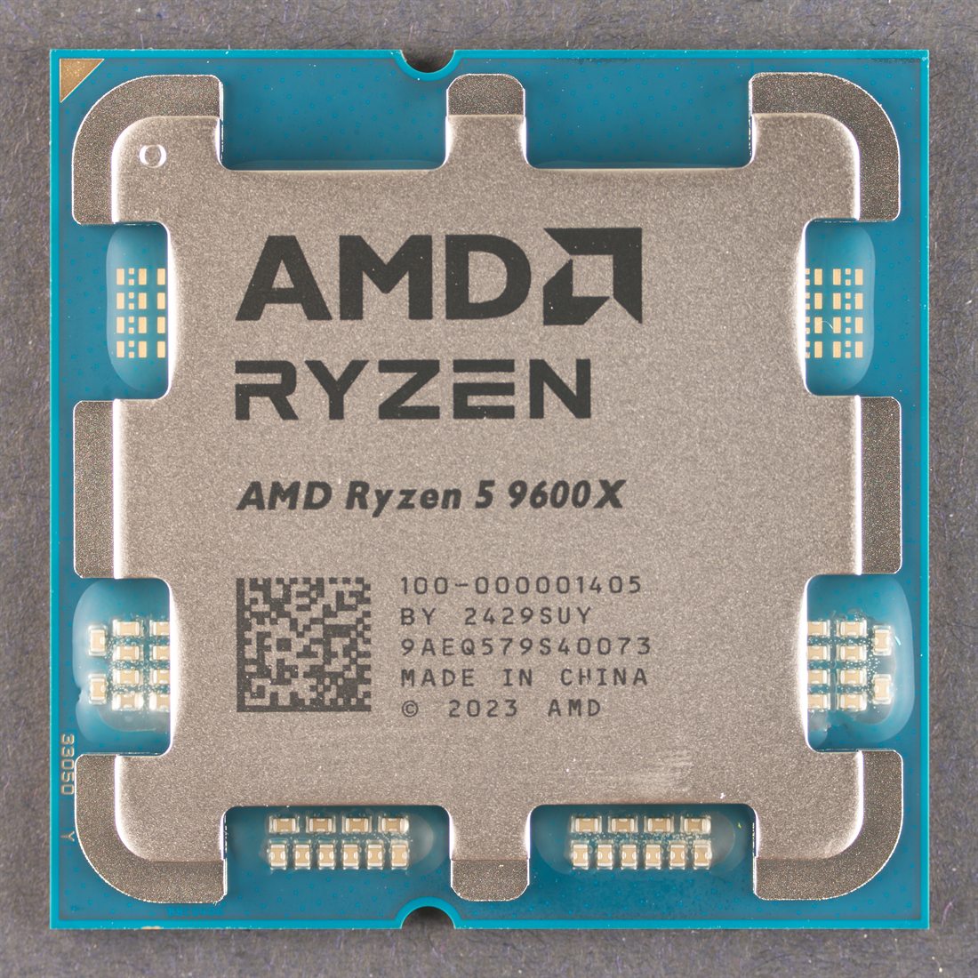The top face of an AMD Ryzen 5 9600X processor — the metal heat
                      spreader stamped with the AMD Ryzen logo over a teal substrate.